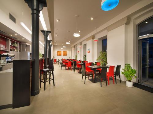 a dining room with red chairs and tables in a restaurant at EA Business Hotel Jihlava in Jihlava