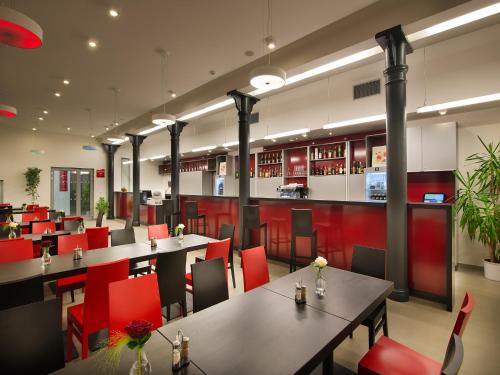 a restaurant with tables and red chairs and a bar at EA Business Hotel Jihlava in Jihlava