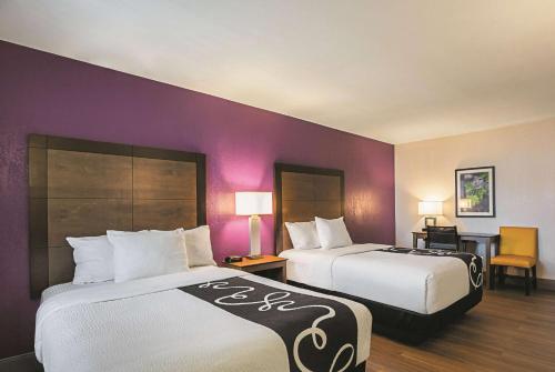 two beds in a hotel room with purple walls at Wingate by Wyndham Galveston Beachfront at the Seawall in Galveston