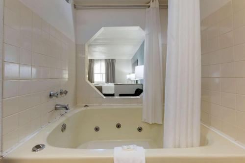uma casa de banho branca com uma banheira e um espelho. em Quality Inn Alexis Rd em Toledo