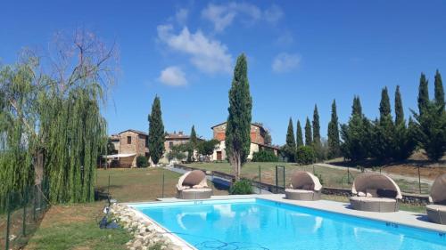 a swimming pool in a yard with trees and houses at I Salici Agriturismo in Badia Agnano