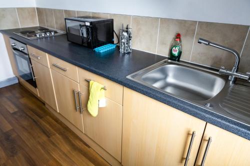 a kitchen with a sink and a microwave at Empress House in Manchester