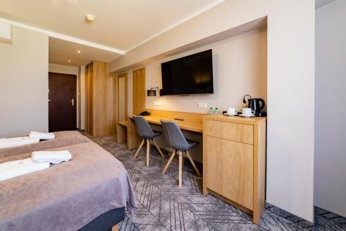 a hotel room with two beds and a desk at Hotel Jubilat in Zamość