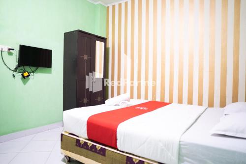 um quarto com uma cama e uma televisão em Hotel Ratu Ayu 2 Lampung Mitra RedDoorz em Tanjungkarang
