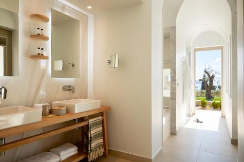 a bathroom with two sinks and a mirror at Eagles Villas - Small Luxury Hotels of The World in Ouranoupoli