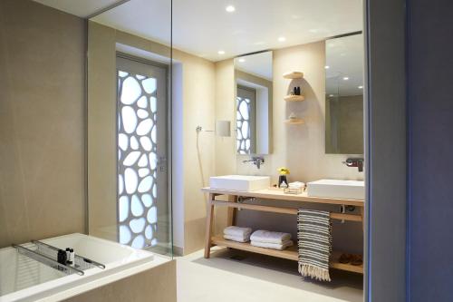 a bathroom with a tub and a sink and a mirror at Eagles Villas - Small Luxury Hotels of The World in Ouranoupoli