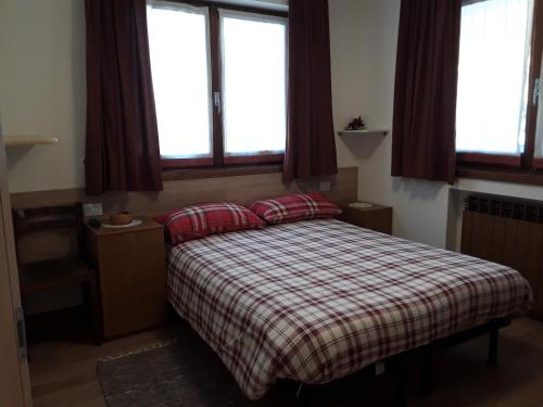 una camera da letto con un letto con una coperta a quadri e due finestre di Residence Ables a Valfurva
