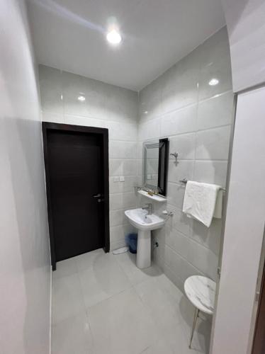 Baño blanco con lavabo y espejo en شقق برج السمو للشقق المفروشة, en Najrán