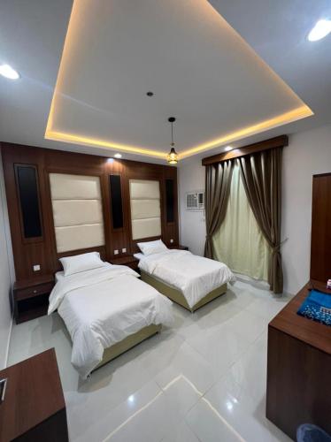 1 dormitorio con 2 camas, escritorio y ventana en شقق برج السمو للشقق المفروشة, en Najrán