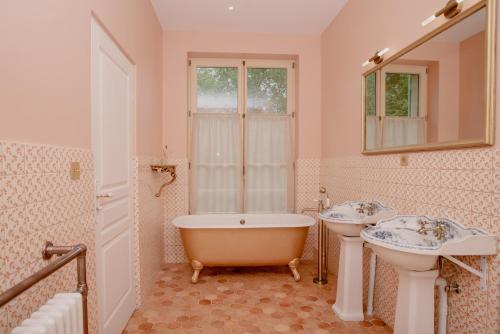 a bathroom with two sinks and a bath tub and a mirror at Domaine du Chateau Vert in Hondainville