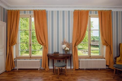 a room with a table and two windows at Domaine du Chateau Vert in Hondainville