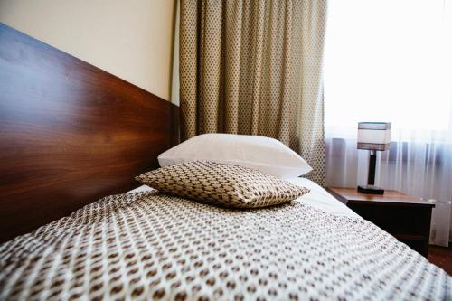 a bed with a wooden headboard and a pillow on it at Hotel Jubilat in Zamość