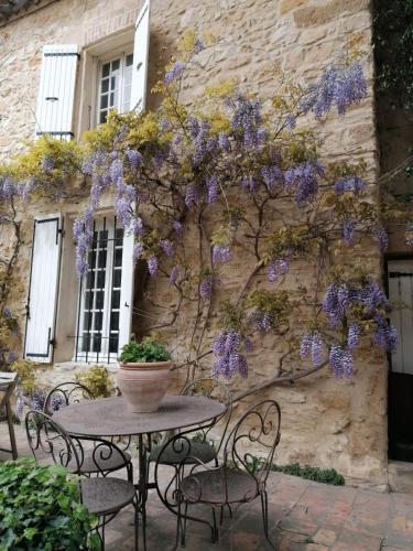a table and chairs in front of a building with purple flowers at MAS DU RECATI in Caderousse