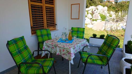 een tafel met groene stoelen en een vaas erop bij House Fantazija in Rab