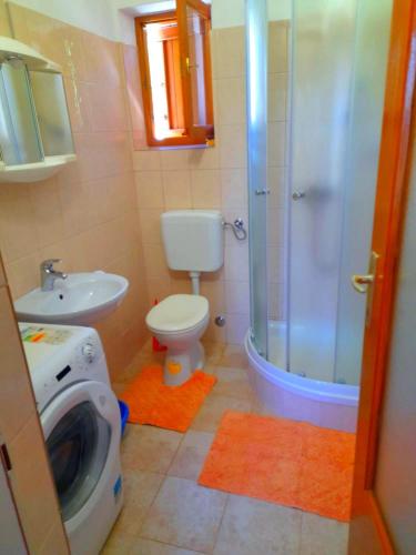 a bathroom with a shower toilet and a washing machine at House Fantazija in Rab