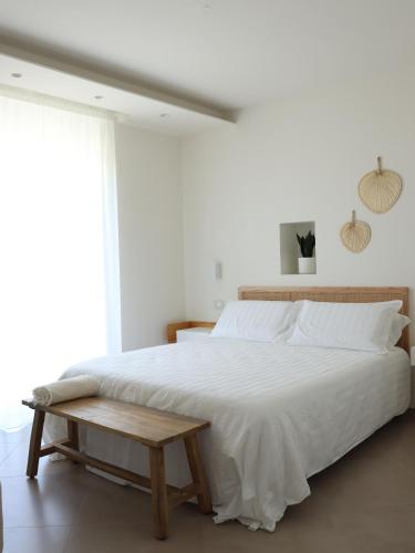 a bedroom with a large white bed with a wooden bench at Residenze Aimone in Vasto