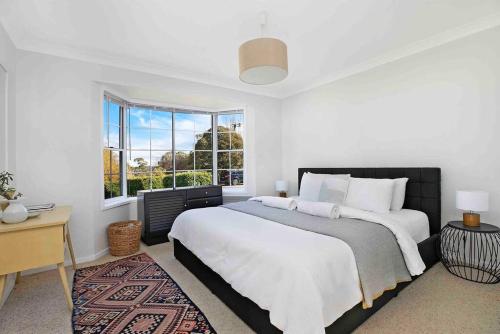 Un dormitorio blanco con una cama grande y una ventana en Home On The Hill- Bowral, en Bowral