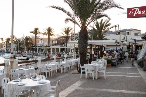 a restaurant with white tables and chairs and a palm tree at CABO DE PALOS ATICO LA GALERA parking in Cabo de Palos