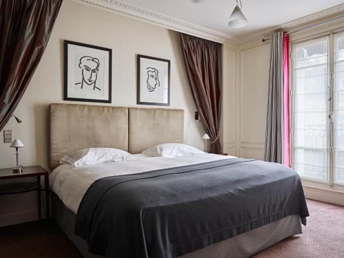 a bedroom with a large bed with two pictures on the wall at La Tremoille Paris in Paris