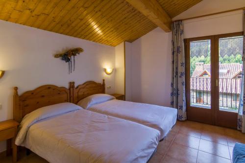 1 dormitorio con 2 camas y ventana en Hostal Cal Mestre en Vilallonga de Ter