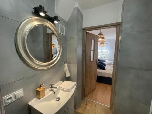 a bathroom with a sink and a mirror and a bed at Kamienica Poznańska 7 in Bydgoszcz