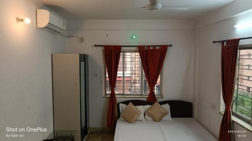 um quarto com uma cama com cortinas vermelhas e uma janela em STAYMAKER Royal Residency em Calcutá