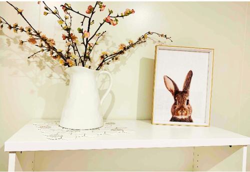 a vase and a picture of a rabbit on a table at Orchard Lodge Wanaka - Relax, Refresh, Recharge in Wanaka