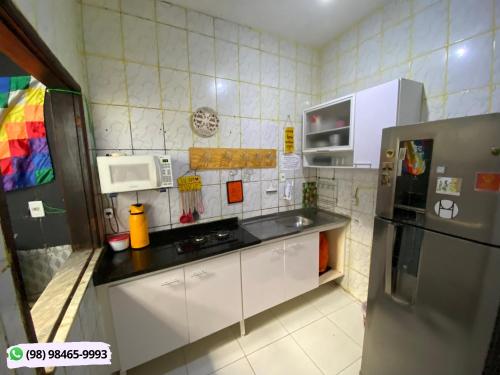 uma cozinha com armários brancos e um frigorífico de aço inoxidável em Guarnicê Hostel em São Luís