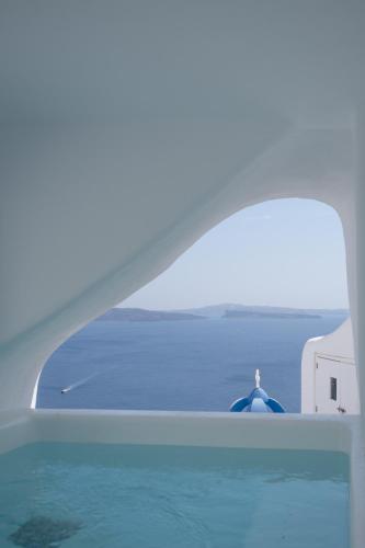 a person standing on top of a window looking at the water at Oia Spirit Boutique Residences in Oia