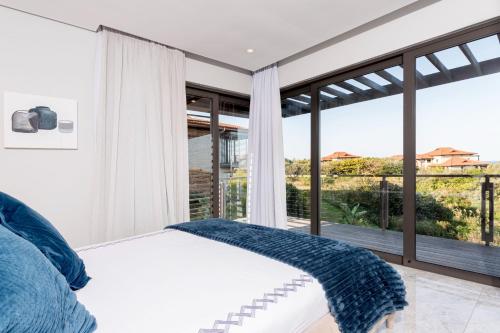 a bedroom with a bed and a large window at 10-11 Ocean’s Edge, Zimbali – 8 Bedroom in Ballito
