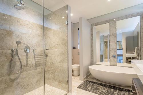 a bathroom with a shower and a tub and a sink at 10-11 Ocean’s Edge, Zimbali – 8 Bedroom in Ballito