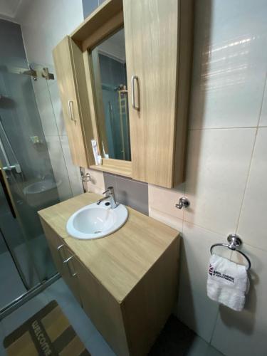 a bathroom with a sink and a mirror and a shower at Bays Lodge, Accra in Accra