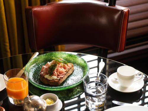 a table with a plate of food on a table with orange juice at J.K. Place Roma - The Leading Hotels of the World in Rome