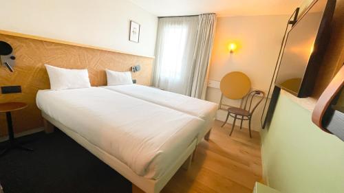 a bedroom with a large white bed and a window at Greet Hotel Colmar in Colmar