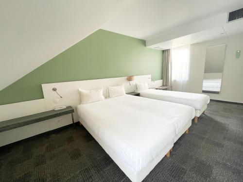 two beds in a hotel room with white sheets at Greet Hotel Colmar in Colmar