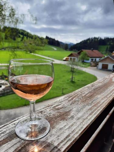 a glass of wine sitting on top of a wooden table at Ferienwohnungen Rössle in Stiefenhofen