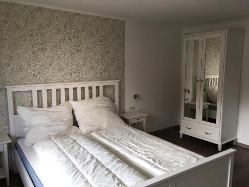 a bedroom with a white bed and a mirror at Ferienwohnungen Rössle in Stiefenhofen