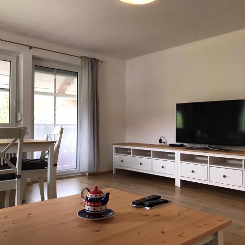 a living room with a flat screen tv and a table at Ferienwohnungen Rössle in Stiefenhofen