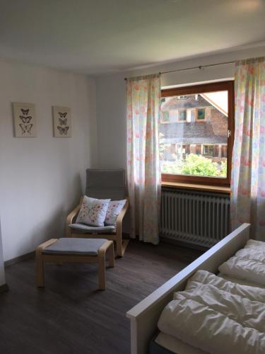 a room with a bed and a chair and a window at Ferienwohnungen Rössle in Stiefenhofen