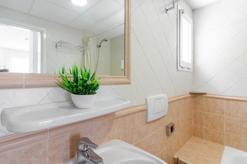 een badkamer met een wastafel, een toilet en een spiegel bij Flatguest Alisios Playa 4 in Corralejo