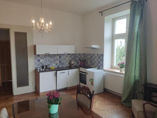 a kitchen with white cabinets and a table and a window at Vila Janáčkova - 1st republic villa in Trutnov