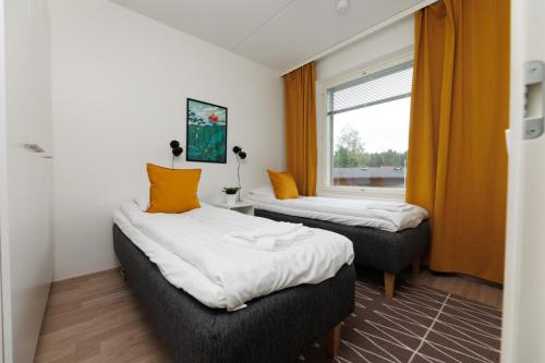 two beds in a room with a window at Hiisi Homes Hämeenlinna Asemanranta in Hämeenlinna