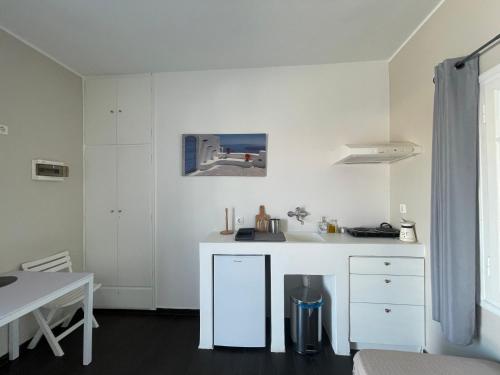 a white kitchen with a sink and a table at AEGEAN VIEW SEASIDE ROOMS AND STUDIOS KEA in Korissia