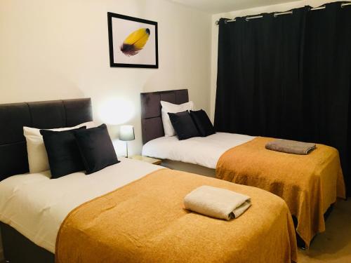 um quarto de hotel com duas camas com cobertores amarelos em Cloud9SA at Woking Central em Woking