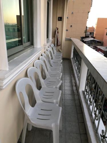 une rangée de chaises blanches assises sur un balcon dans l'établissement THE MANSION - BACKPACKERS Near AIRPORT, à Manille