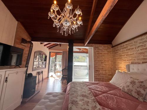a bedroom with a bed and a chandelier at Pousada Dona Bendita in Monte Verde