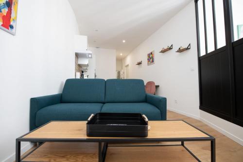 een woonkamer met een blauwe bank en een tafel bij L'Arty - Très joli studio moderne place Valmy in Lyon