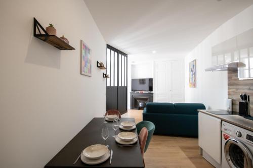 een keuken en een woonkamer met een tafel en een bank bij L'Arty - Très joli studio moderne place Valmy in Lyon