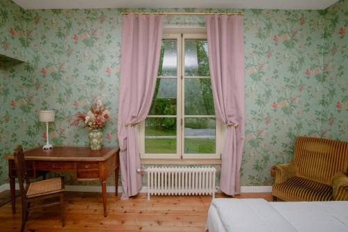 a bedroom with pink curtains and a desk and a window at Domaine du Chateau Vert in Hondainville