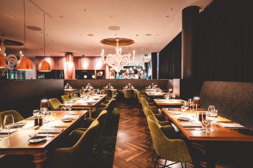 a restaurant with long tables and chairs and a chandelier at Kameha Grand Bonn in Bonn